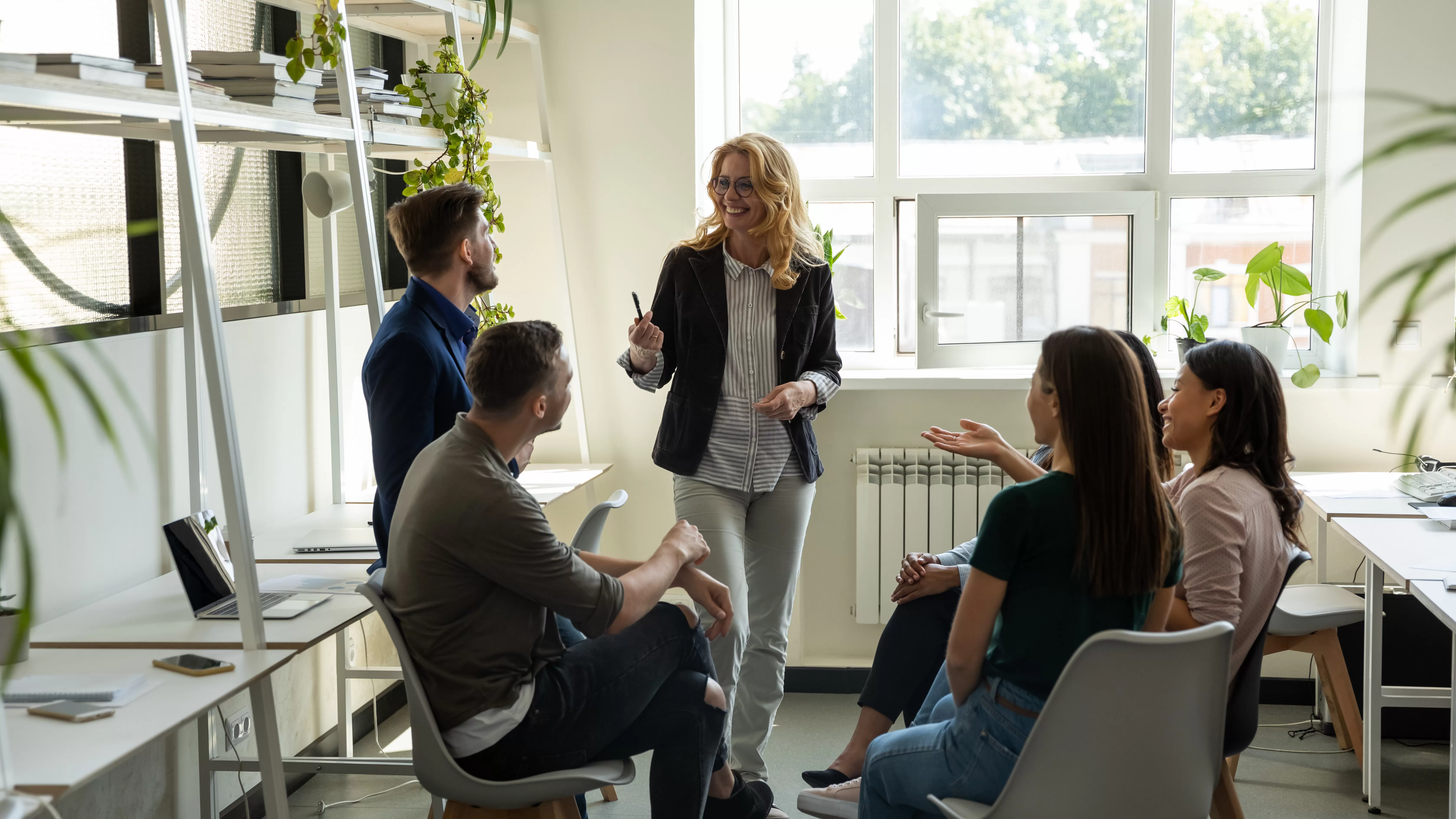 HR leader facilitating a small group discussion with employees during a collaborative workplace meeting.