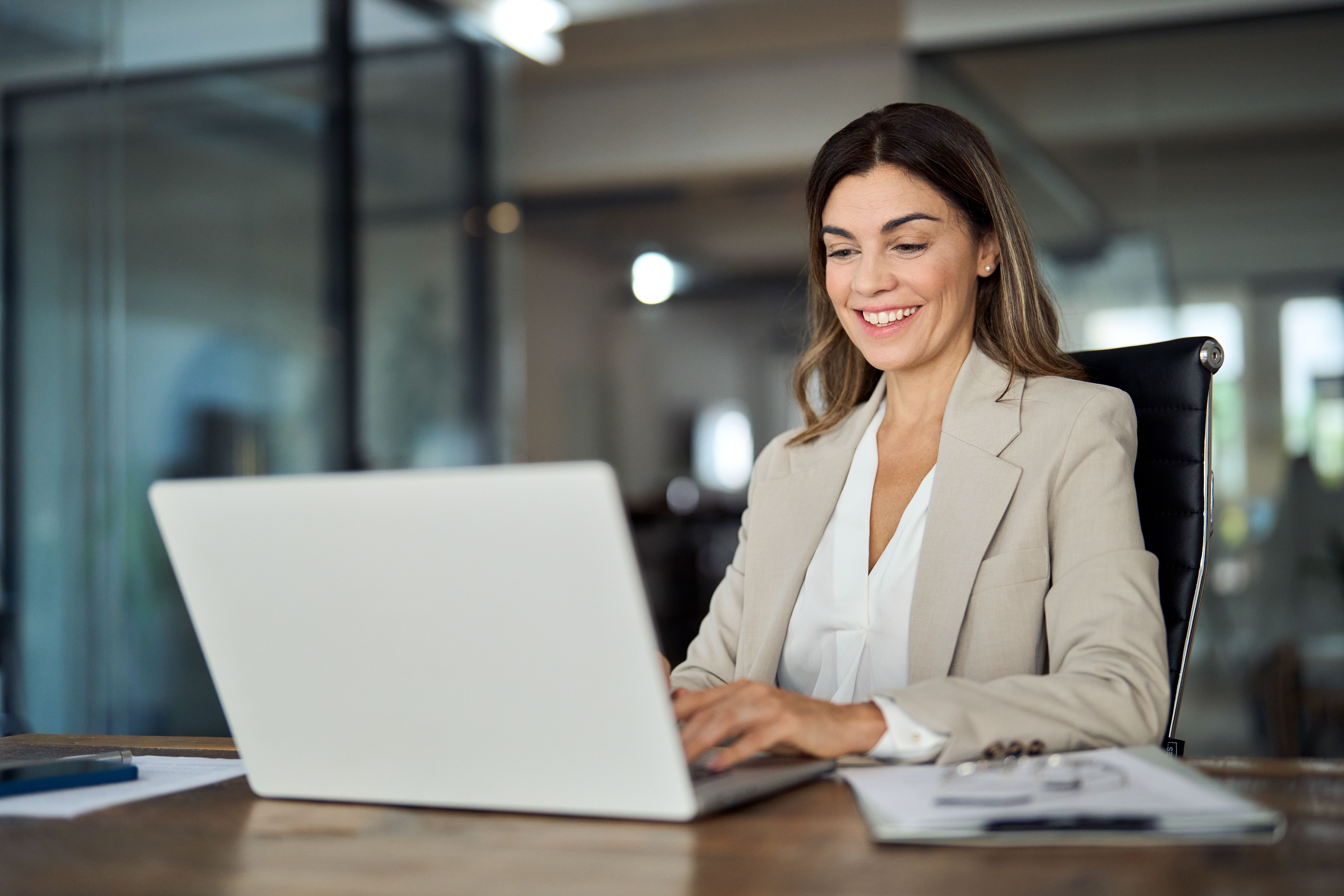 HR manager working on performance management tasks using a laptop in a modern office setting